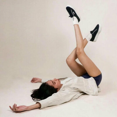 woman lying down on the floor and playing with her black sneakers